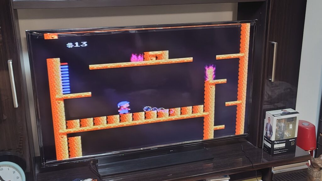 ファミコン『迷宮組曲』をテレビでプレイ中の画面。オレンジ色のステージにキャラクターが進んでいる